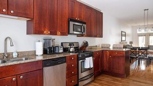 A modern kitchen with wooden cabinets, stainless steel appliances, and a granite countertop. - Urban Oasis - Walk to Restaurants, Transit & More! (Chicago)