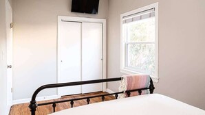 A bedroom with a bed, a window with blinds, a door, and a TV mounted on the wall. - Urban Oasis - Walk to Restaurants, Transit & More! (Chicago)