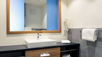 A modern bathroom with a large mirror, white sink, and a towel rack.