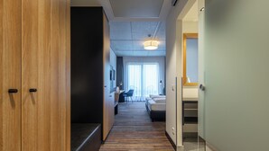 Un pasillo de hotel con un armario de madera, una alfombra a rayas, una cama, un escritorio y una escalera.
