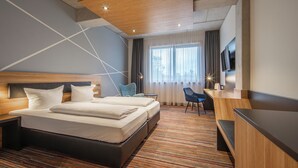 Habitación de hotel con una cama grande, un escritorio, una silla y un televisor.