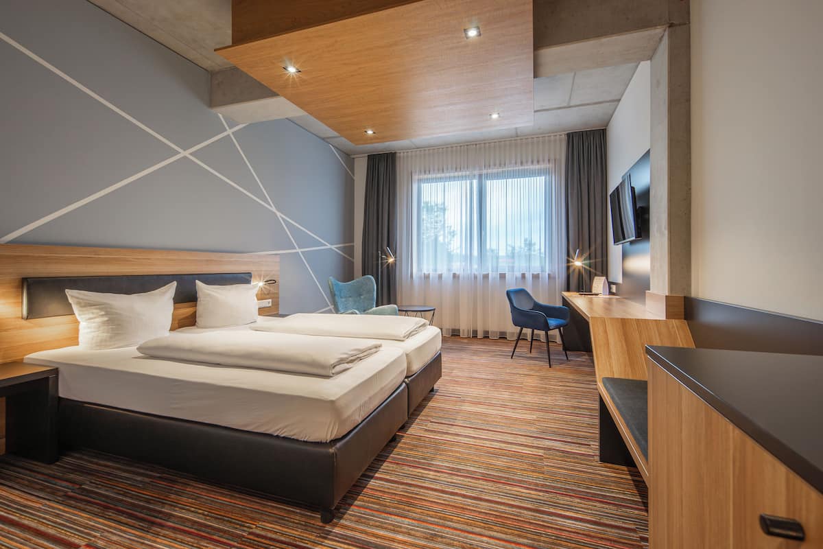 Habitación de hotel con una cama grande, un escritorio, una silla y un televisor.