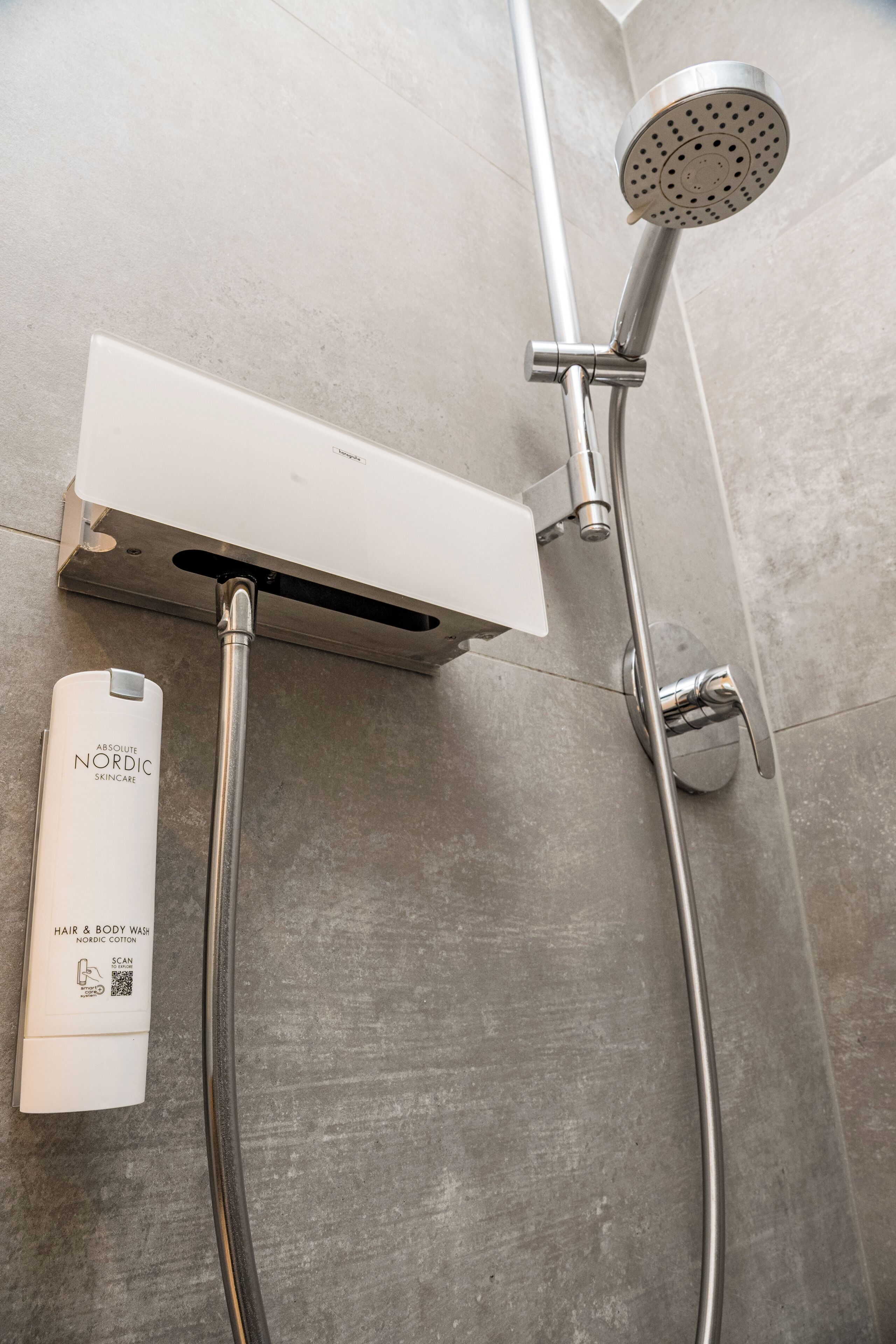 A shower with a handheld showerhead and a wall-mounted control panel.