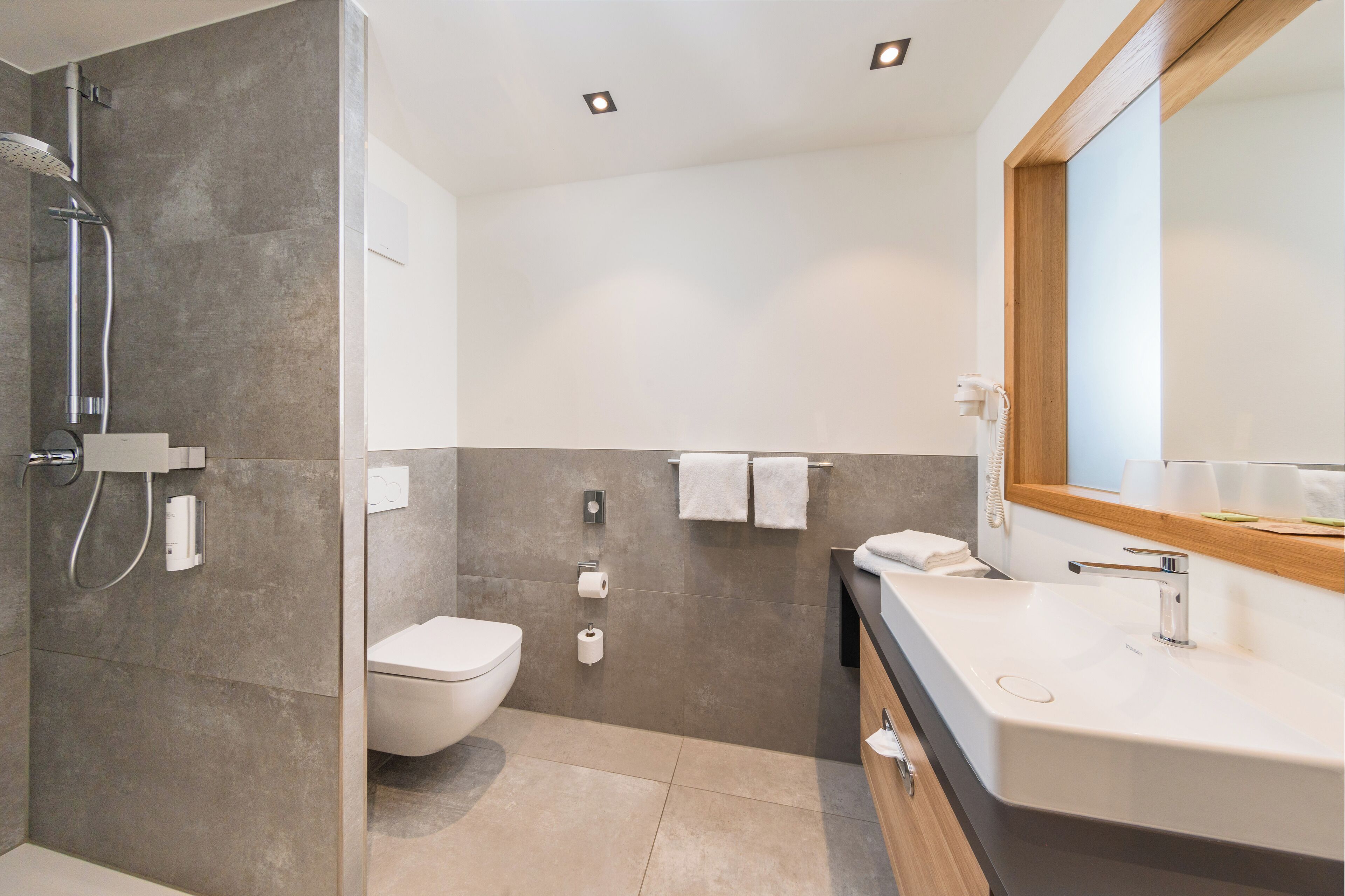 A modern bathroom with a shower, toilet, and sink.