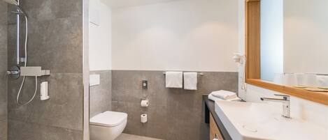 A modern bathroom with a shower, toilet, and sink.