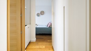 A narrow hallway leading to a bedroom with a bed and two wall decorations.
