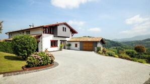 A two-story house with a paved driveway, a garage, and a well-maintained garden.