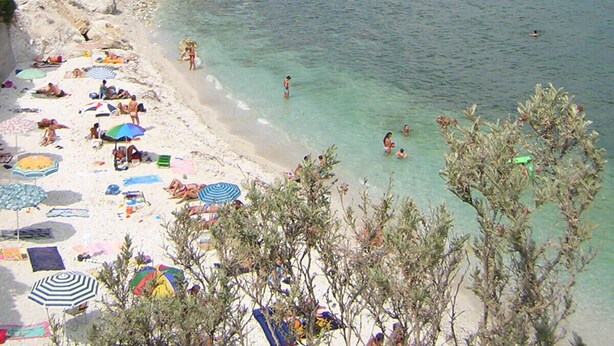 A beach with clear turquoise water, people sunbathing and swimming, and boats in the distance. - Two-room apartment with garden and private parking space (Portoferraio)