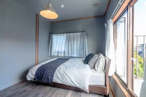 Un dormitorio con cama, ventana y una lámpara en el techo.