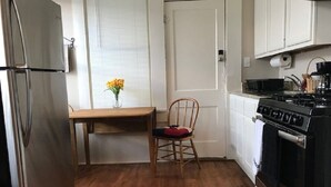 Una cocina compacta con refrigerador, estufa y mesa de comedor de madera.
