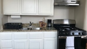 Una cocina con gabinetes blancos, estufa y lavabo.