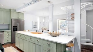 Una cucina moderna con una grande isola, elettrodomestici in acciaio inossidabile e una scala a chiocciola.