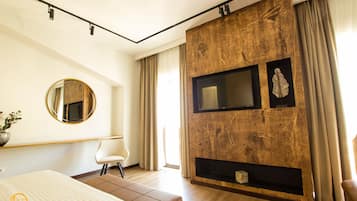 Un dormitorio moderno con una cama grande, un espejo redondo, un televisor de pantalla plana y una chimenea.