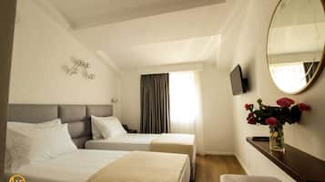 A hotel room with two beds, a large mirror, a TV, and a vase with flowers.