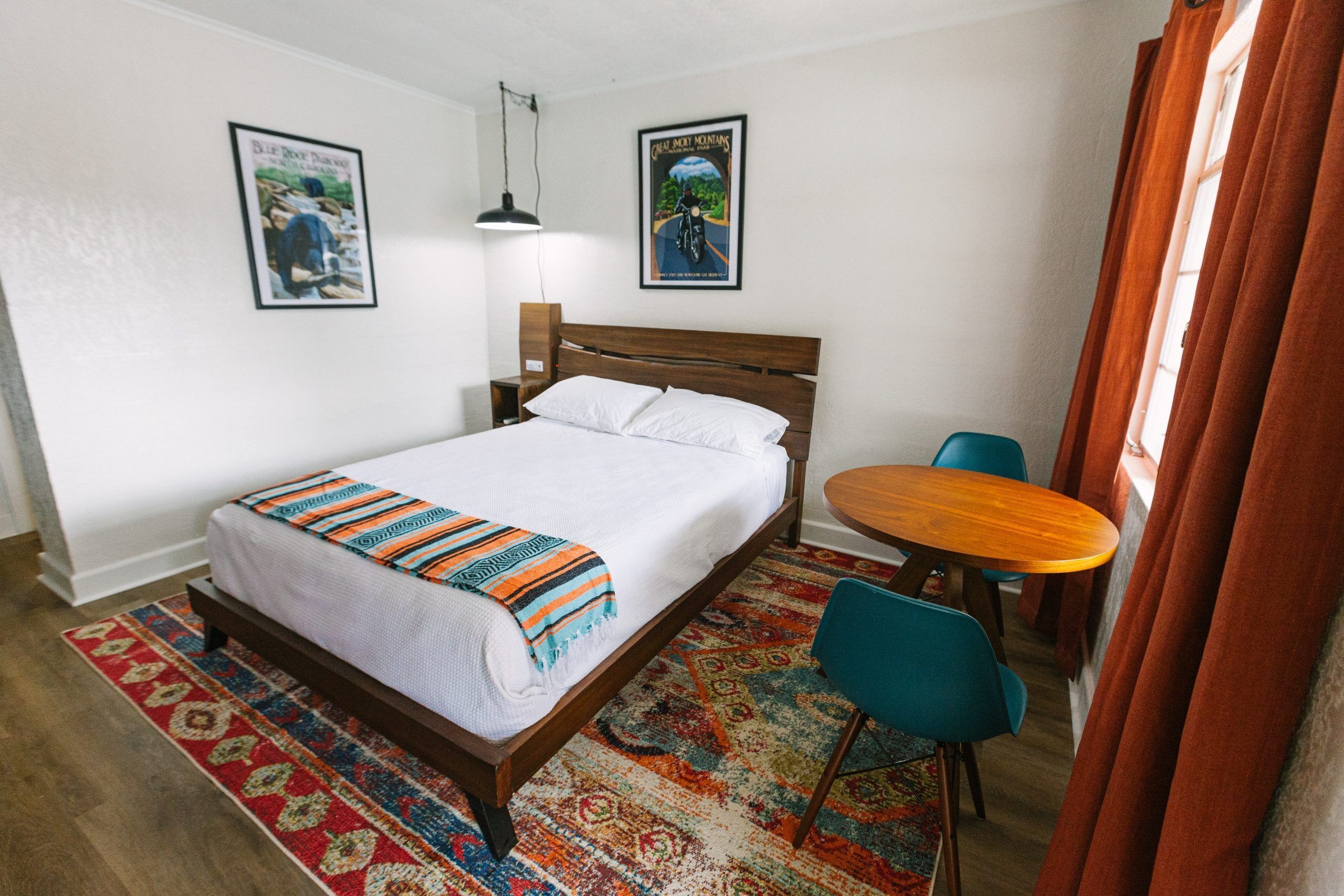 Una habitación de hotel ordenada con una cama, una mesita redonda y dos sillas.