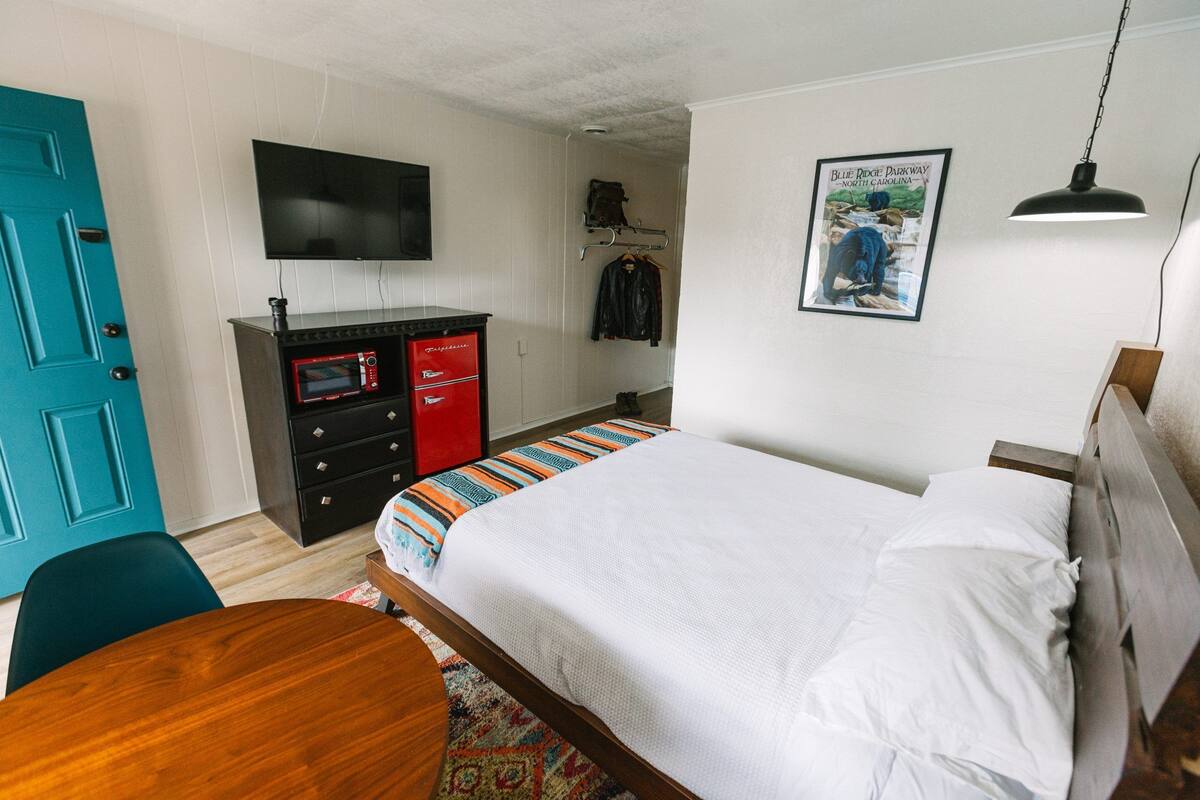 Ein Schlafzimmer mit Bett, Schreibtisch, Fernseher und Kommode.