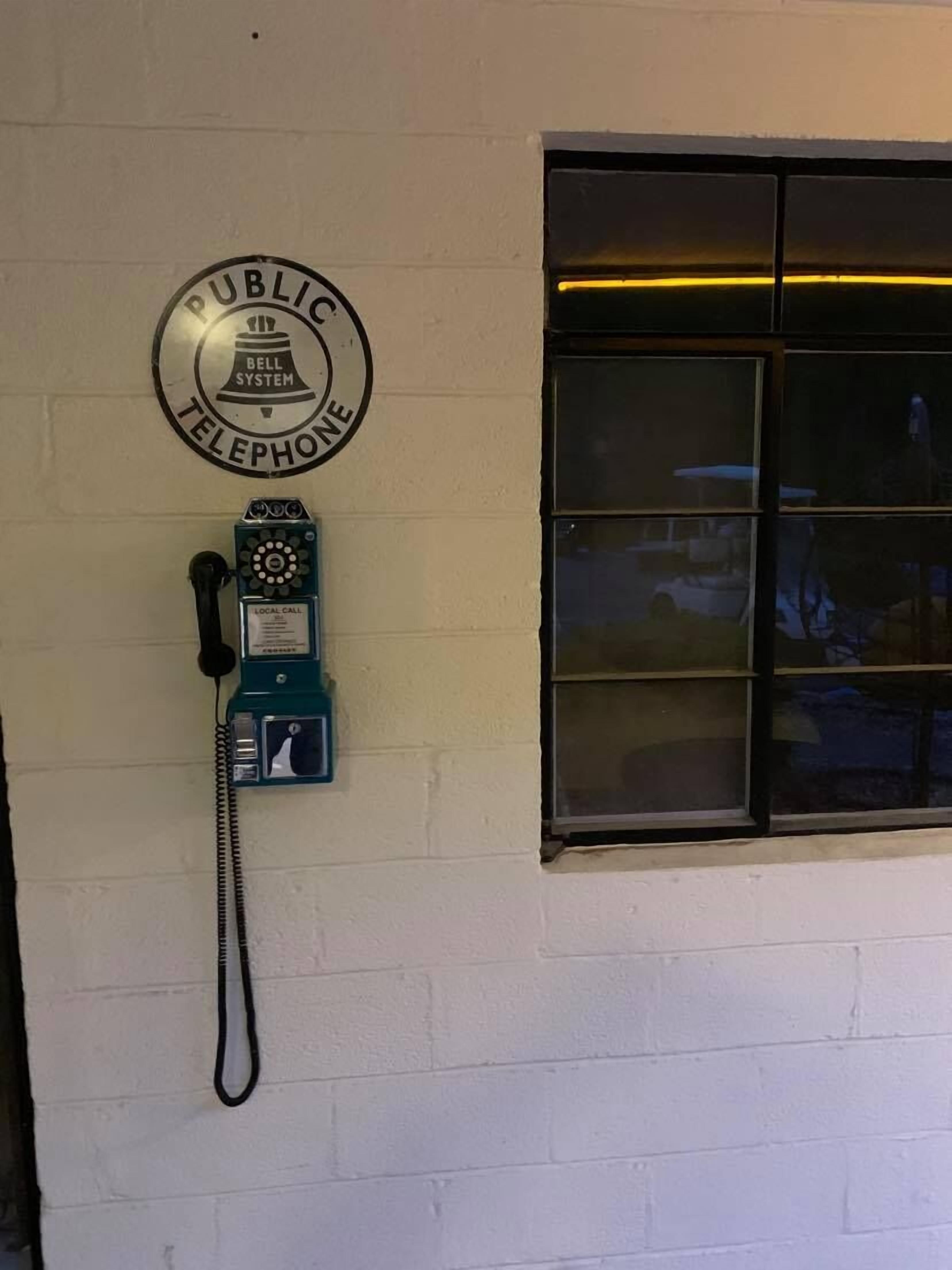 A public telephone with a sign above it that reads "PUBLIC TELEPHONE."