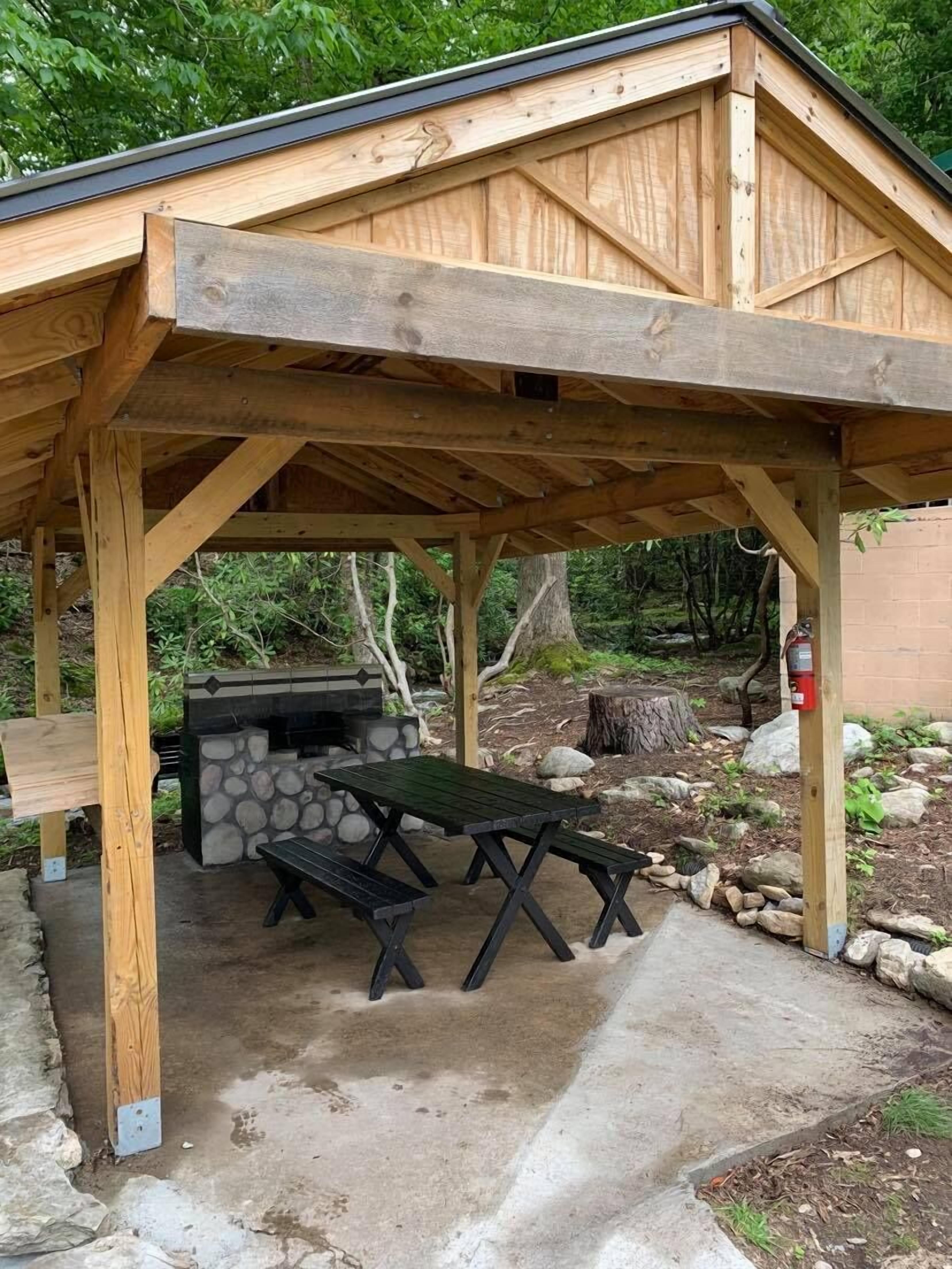 Un espacio al aire libre techado con una parrilla y una mesa de picnic.