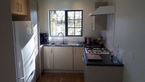 A compact kitchen with a refrigerator, sink, stove, and cabinets.