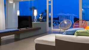 Ein modernes Wohnzimmer mit großem Fernseher, einer Sitzecke und Blick ins Freie.