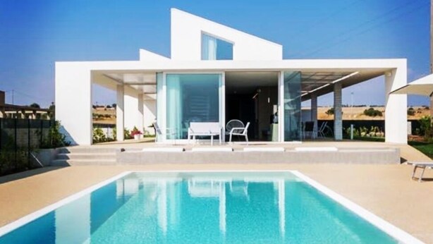 Ein modernes Haus mit Schwimmbecken vor der Fassade.