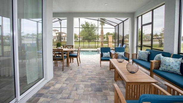A covered patio area with a pool, seating, and large windows. - 8905 New Luxury Solara Resort Private Pool (Kissimmee)