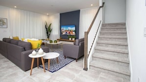 A modern living room with a grey sofa, a coffee table, and a TV mounted on the wall. - 8905 New Luxury Solara Resort Private Pool (Kissimmee)