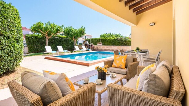 Un espace extérieur avec une piscine, des chaises longues, une table à manger et des meubles en osier.