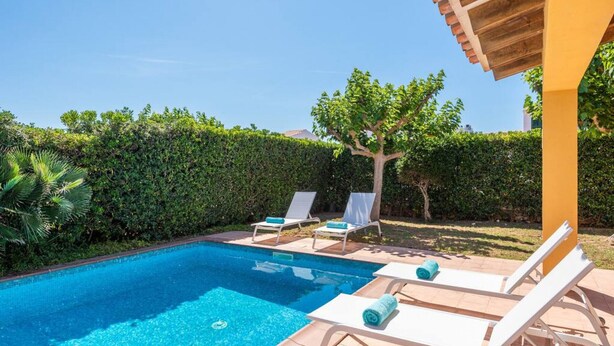 Una piscina con sillas de descanso y una pérgola.