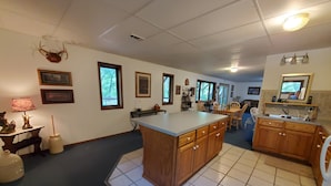 A spacious kitchen with a large island, wooden cabinets, and a dining area with chairs. - Hog Heaven-Lower Level of Private Home- Lakefront (Garfield)