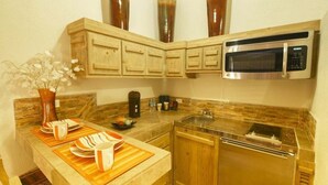 Una cucina compatta con mobili in legno, un forno a microonde in acciaio inox e una lavastoviglie.