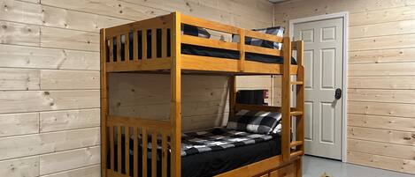 A bunk bed with a wooden frame and a lower bunk with a mattress and pillows. There is a door with a lock on the right side.