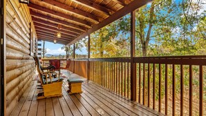 A wooden deck with a railing, a table, and two chairs.