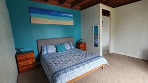 A bedroom with a bed, nightstands, a dresser, a painting, and a door. - Catalina Coastal Getaway / Family friendly home (Catalina)