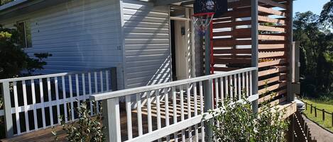 A house with a porch, a basketball hoop, and a wooden fence.