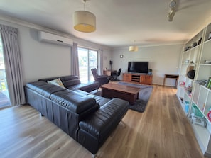Ein modernes Wohnzimmer mit einer Ledersofa, einem Holztisch, einem Fernseher und einem Bücherregal.