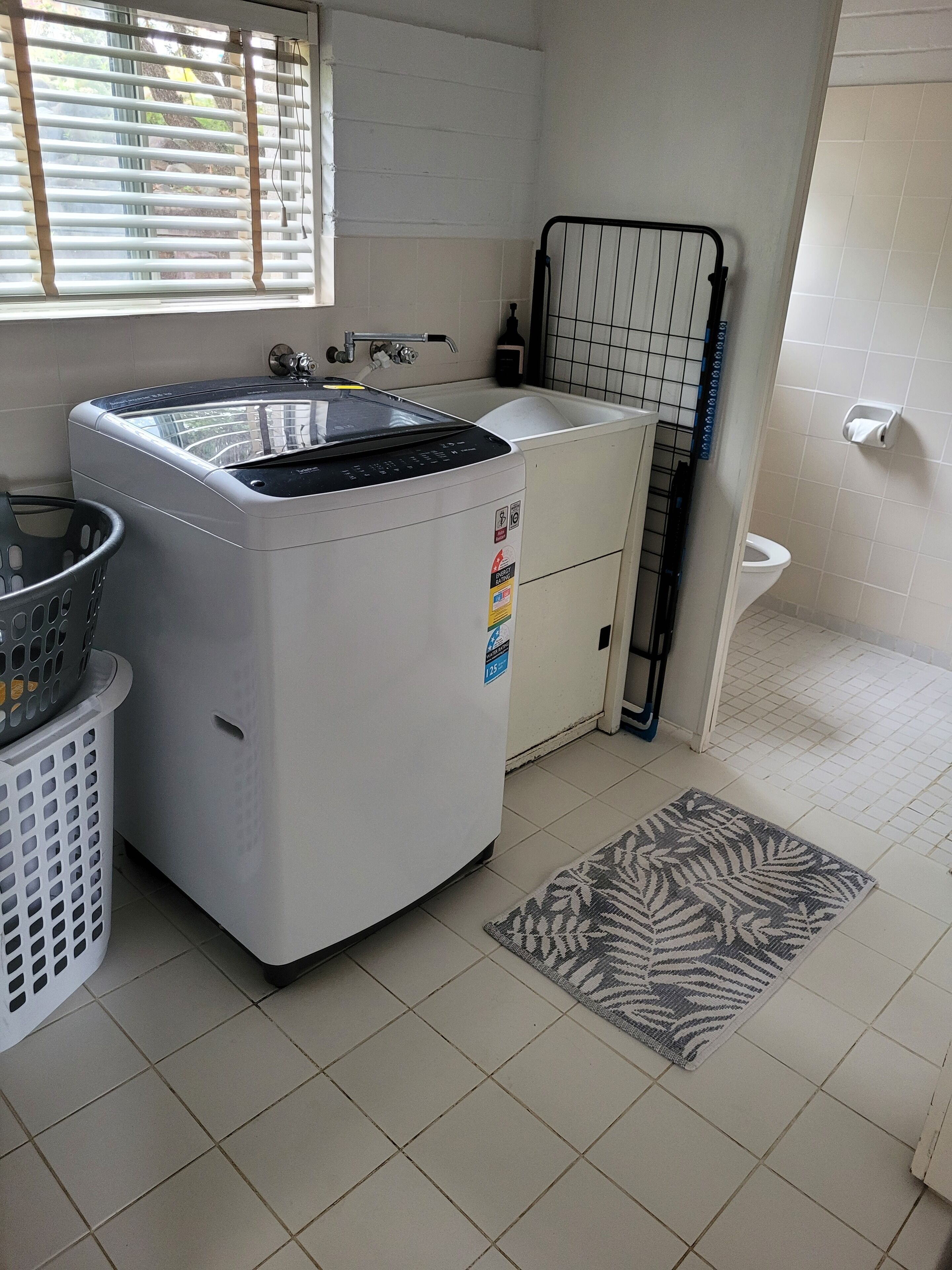 Een kleine wasruimte met een wasmachine, een spoelbak en een klein kastje.