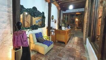 Un interior acogedor con un sofá, un espejo y techo de madera.