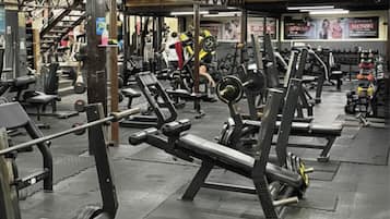 Une salle de sport équipée de divers appareils d’exercice, notamment des bancs et des machines de musculation.