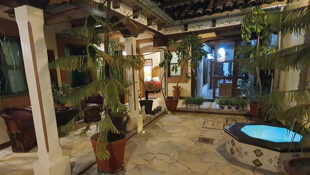 Une cour intérieure avec un sol en pierre, des plantes en pot, un jacuzzi et une vue sur la pièce adjacente.