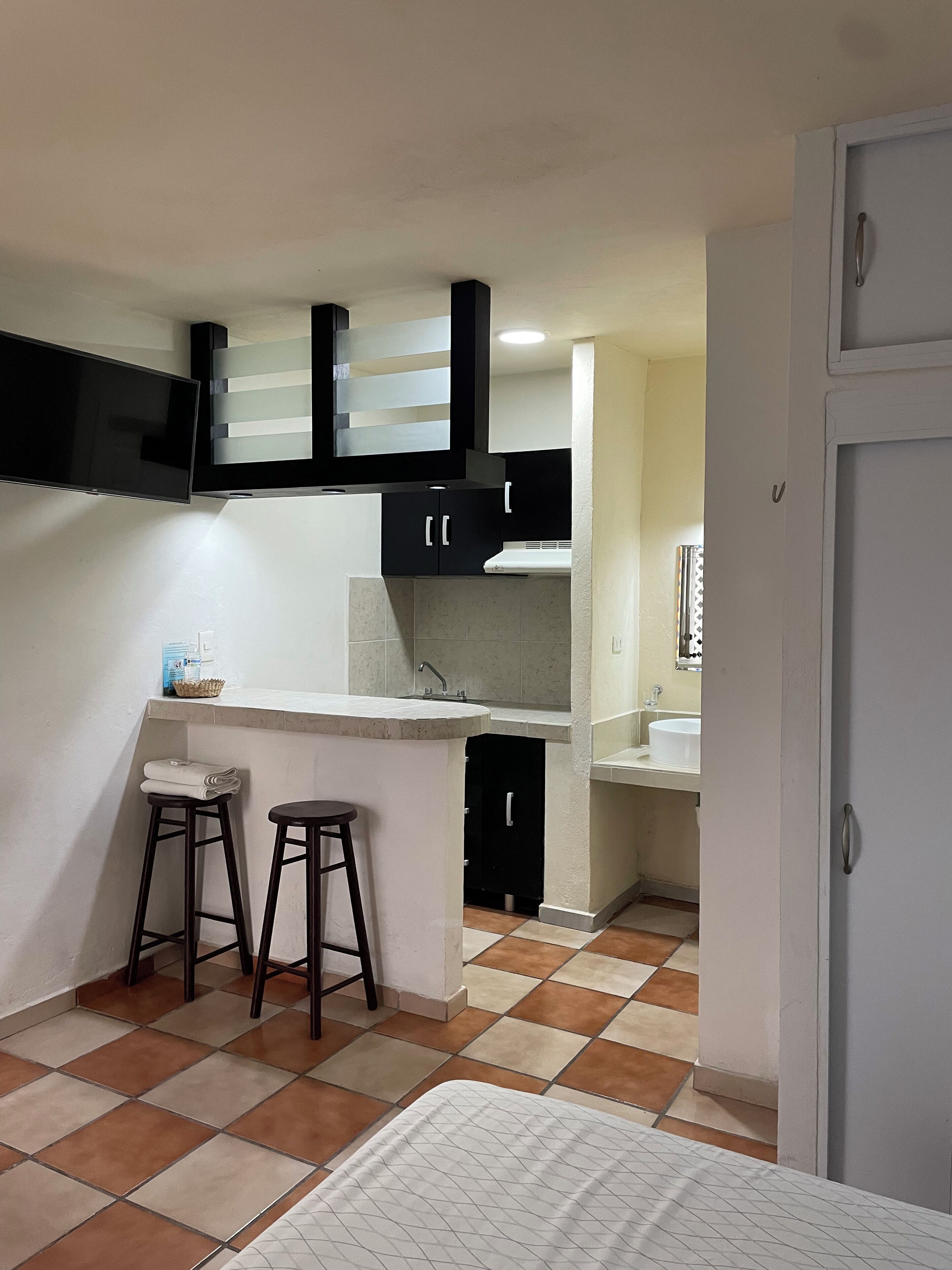 A compact kitchen with a built-in stove, a sink, and two stools.