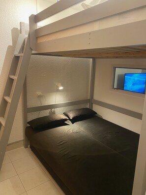 Een stapelbed met een televisie op het bovenste bed.