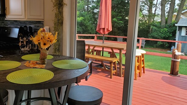 Una cocina con una isla central, un comedor con mesa y sillas, y una terraza con mesa y sillas.