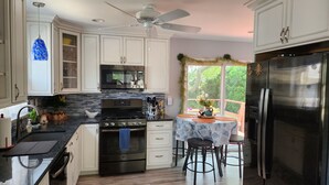 Una cocina moderna con armarios blancos, electrodomésticos de acero inoxidable y un comedor con mesa y sillas.