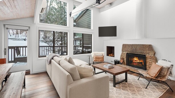 Una sala de estar moderna con chimenea, ventanas amplias y un rincón de estar acogedor.