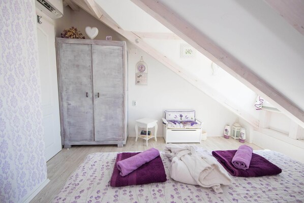 A bedroom with a bed, a wardrobe, a small bedside table, and a window.