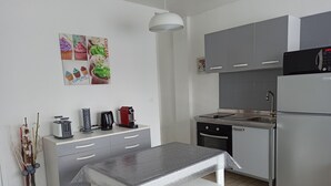 A modern kitchen with grey cabinets, a stainless steel refrigerator, a coffee maker, and a toaster. - Les Chevalets II/ University/Louvre/Bollaert (Lens)