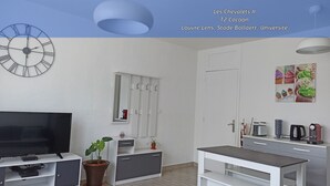 A modern room with a large wall clock, a television, a desk, a coffee machine, and a mirror. - Les Chevalets II/ University/Louvre/Bollaert (Lens)