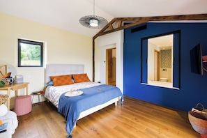 A bedroom with a bed, a desk, a chair, a window, and a mirror.