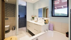 Ein modernes Badezimmer mit einer Badewanne, einem großen Spiegel und einem Fenster.